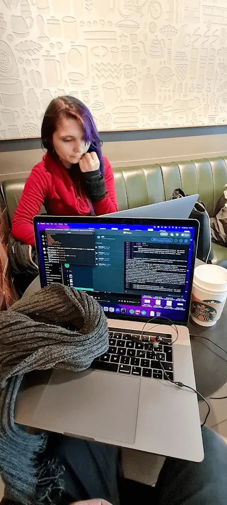 Eli junto a una mesa chica con dos computadores
